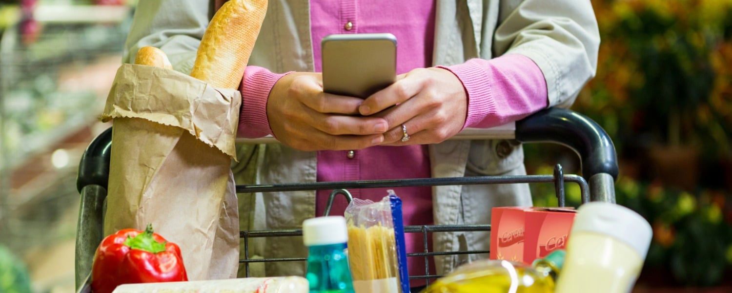 Digital Marketing for Grocers | Grocery Store Digital Marketing | Woman Holding Phone while pushing cart